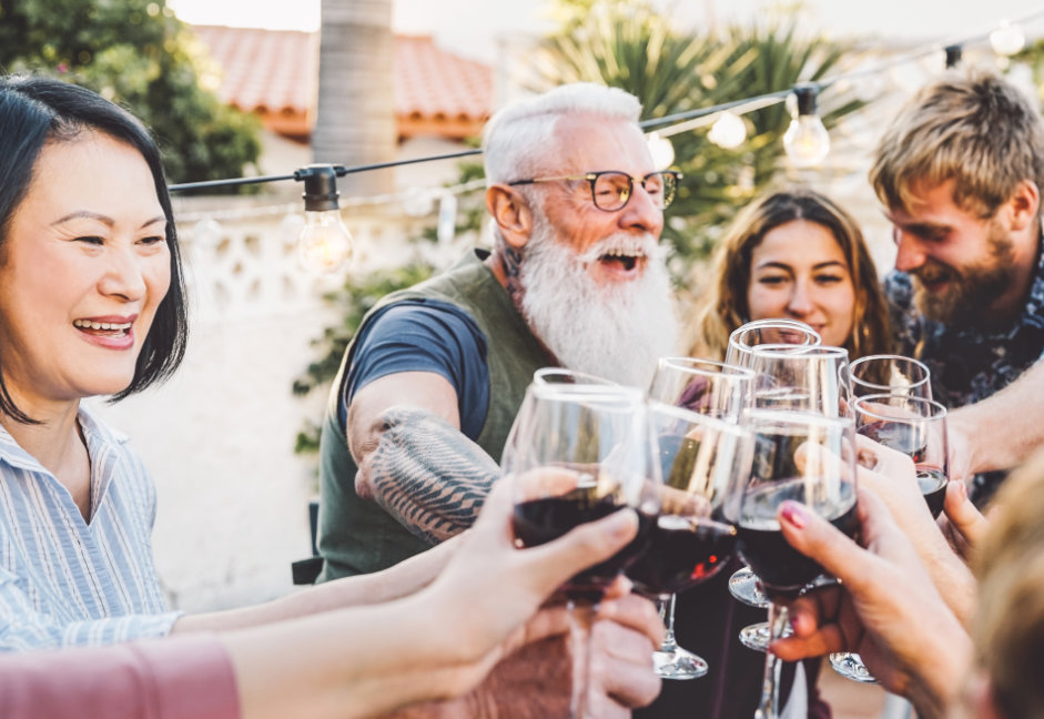 Happy family cheering and toasting with red wine glasses at dinn